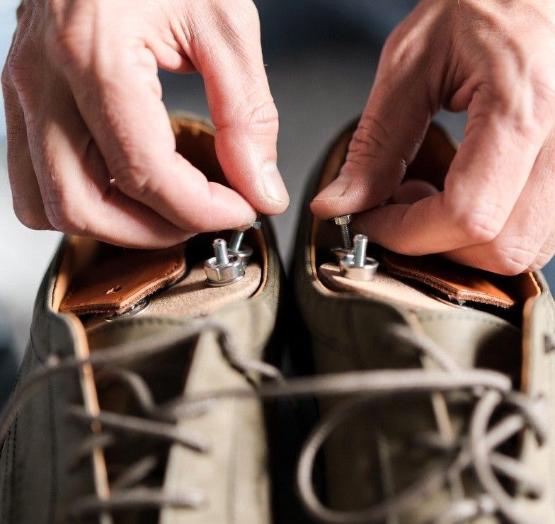 a person adjusting or repairing orthotics in their shoes